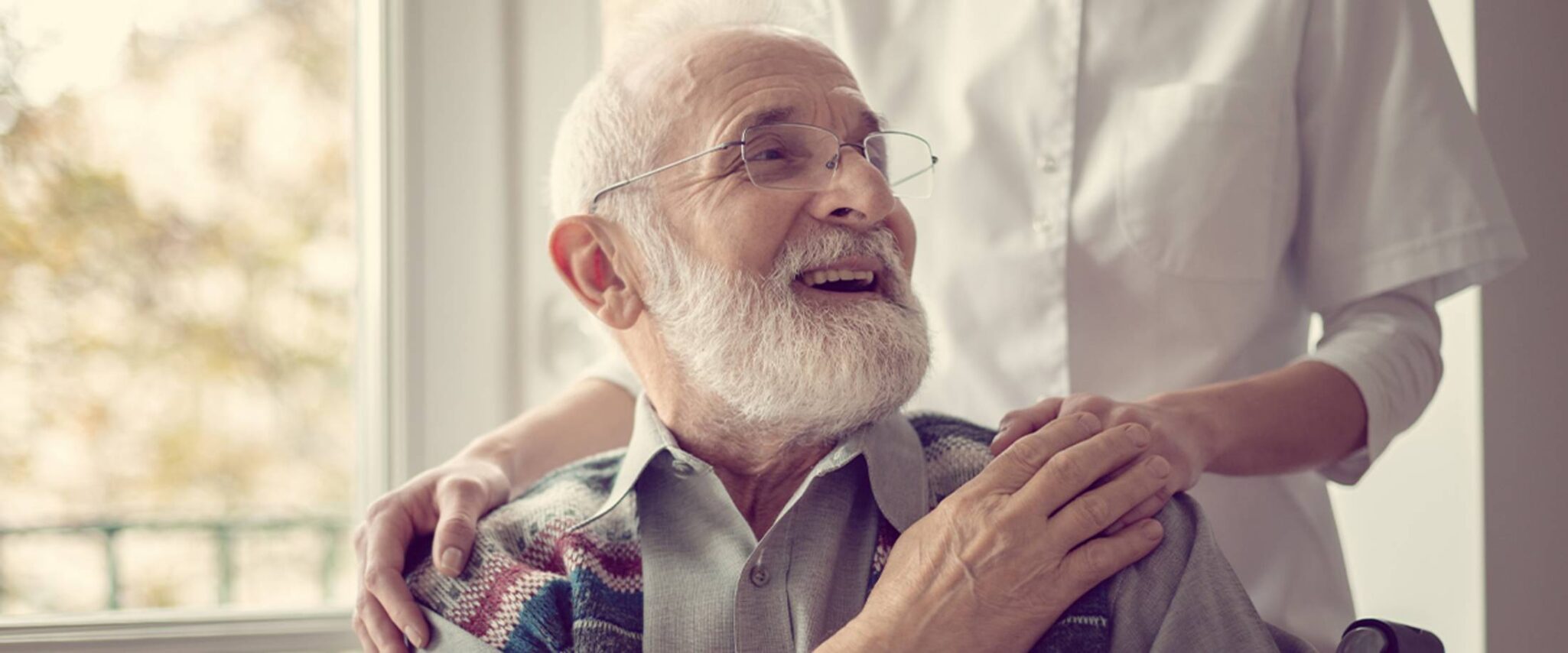 elderly man in a wheelchair with a healthcare worker assisting him