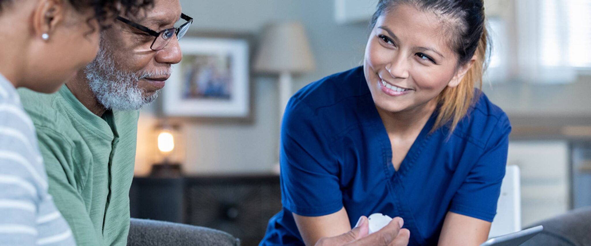 A health care professional sits down with a senior couple to talk about medication management