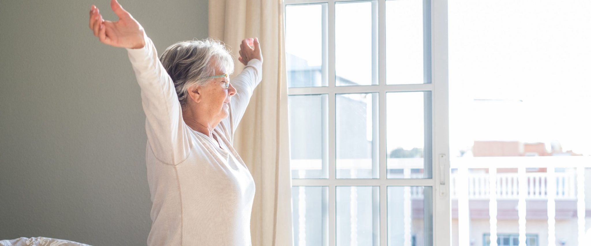 Senior woman stretching in front of window