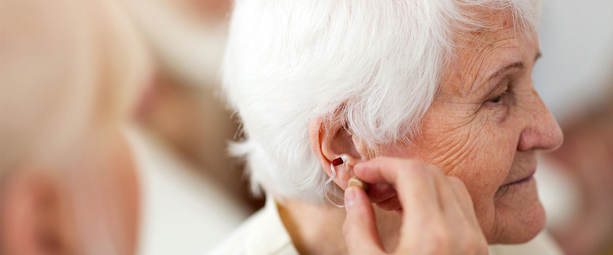 Senior woman inserting hearing aid