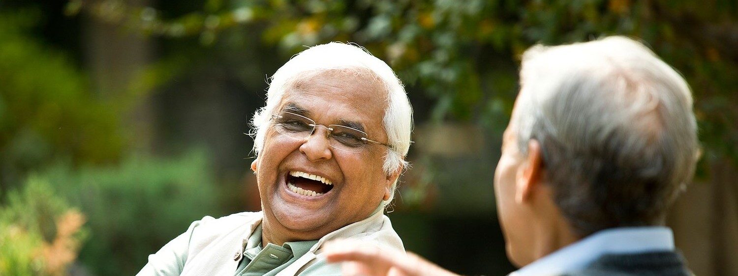 two older men sitting outside laughing