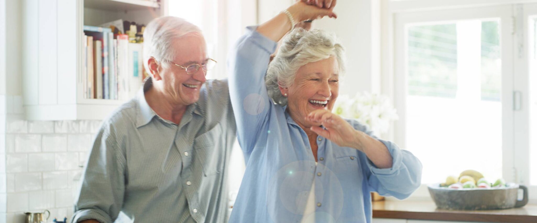 a senior couple dancing in the kitchen of their senior apartment