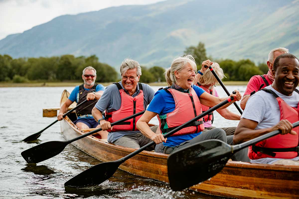 A group of older adults paddling in 2 canoes side by side