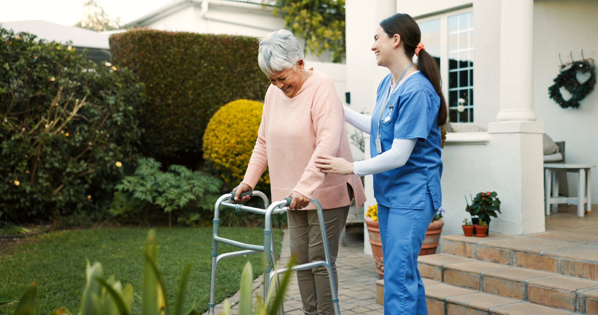Female healthcare worker assisting senior woman with walker